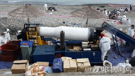 여수 만성리 검은모래 해수욕장에서 자갈세척기로 기름 제거작업을 벌이는 모습./사진=양영권 기자