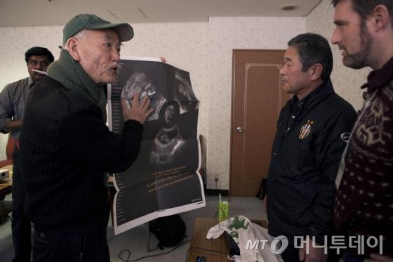 윤호섭 교수(왼쪽)가 후쿠시마 사고 피해자인 전 낙농업자 하세가와 켄이치(Kenichi Hasegawa)씨에게 자신이 디자인한 탈핵 포스터를 보여주고 있다.