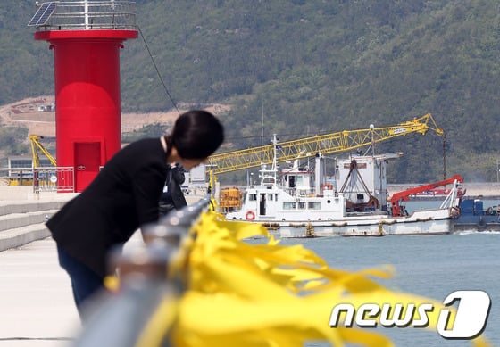 세월호 여객선 침몰 사고 발생 10일째인 25일 전남 진도군 팽목항 앞바다에서 수중 구조작업 장비인 다이빙벨을 실은 바지선이 사고해역으로 향하는 모습이 실종자들의 무사생환을 기원하는 노란 리본 사이로 보이고 있다.2014.4.25/뉴스1 © News1   한재호 기자