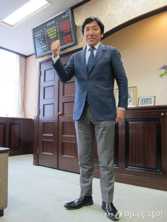 스가와라 잇슈 재무 부대신은 6월24일 도쿄 재무부 청사에서 인터뷰 후 일본의 경제지표를 알리는 모니터를 엄지손가락으로 가리키며 자신있는 포즈를 취했다.