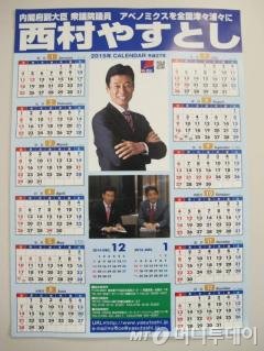 니시무라 야스토시 내각부 부대신 사무실에 붙어있는 선거홍보용 달력. 아베노믹스를 전국으로 확대시키겠다는 구호와 함께 아베 총리와 함께 찍은 사진을 부각시켰다.