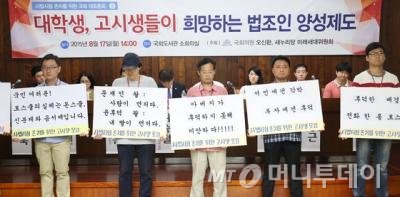 17일 서울 여의도 국회도서관에서 열린 오신환 의원-새누리당 미래세대위원회 주최 '대학생·고시생들이 희망하는 법조인 양성제도' 토론회에서 사법시험 존치를 위한 고시생모임 소속 고시생들이 로스쿨 출신 딸의 대기업 취업을 청탁한 윤후덕 새정치민주연합 의원을 규탄하는 피켓시위를 벌이고 있다. /사진= 뉴스1