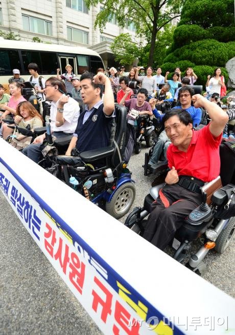 전국장애인차별철폐연대 회원들이 11일 오전 서울 종로구 북촌로 감사원 앞에서 열린'장애인과 가난한 사람들의 생존권 말살하는 감사원 규탄 기자회견'에서 구호를 외치고 있다.  이날 참가자들은 "감사원의 복지사업 재정지원실태 관련 감사보고서는 겉으로는 재정효율화 및 복지사각지대 해소를 목적으로 하지만 그 결과는 장애인과 가난한 사람들의 숨통을 조이는 결과를 낳을 것이다"라고 주장했다./사진= 뉴스1