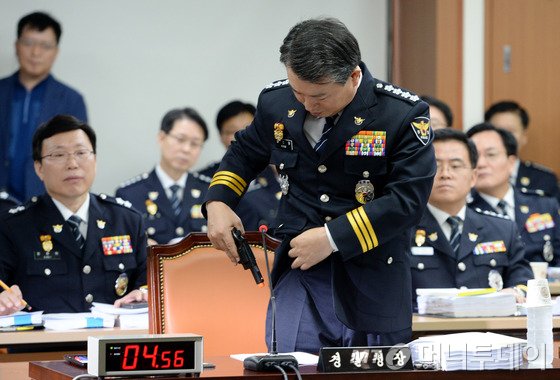 강신명 경찰청장이 14일 오전 서울 서대문구 통일로 경찰청에서 열린 국회 안전행정위원회의 경찰청 등에 대한 국정감사에서 '검문소 총기 사건' 관련 질의를 하던 유대운 새정치민주연합 의원의 권총 격발 시연 요구로 모의 권총을 들어보이고 있다. 2015.9.14/뉴스1