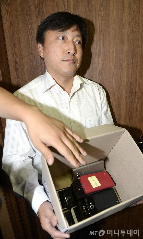 8일 오후 서울 관악구 중앙선거관리위원회 관악청사에서 국회의원선거구획정위원회 전체회의가 열린 가운데 획정위 관계자가 김대년 위원장을 비롯한 위원들의 휴대폰을 수거해 들고 있다. 2015.10.8/뉴스1  <저작권자 © 뉴스1코리아, 무단전재 및 재배포 금지>