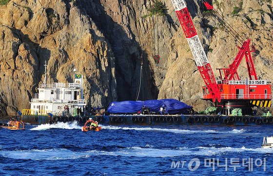 낚시어선 돌고래호 전복 사고 닷새째인 지난달 9일 오후 해경이 크레인이 설치된 바지선(480t)을 이용해 돌고래호를 인양하고 있다. 인양된 돌고래호의 선체는 일부 파손됐다./사진=뉴스1