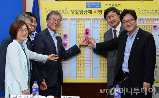 새정치민주연합 문재인 대표가 8일 서울 여의도 국회에서 열린 생활임금제 확산을 위한 토론회에서 참석자들과 함께 생활임금제 시행 지자체 진행현황판에 꽃을 달고있다. 2015.7.8/사진=뉴스1