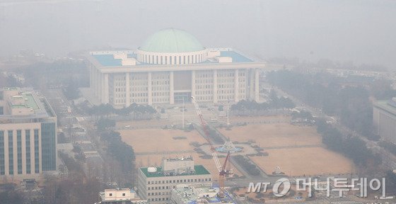 서울의 미세먼지 농도가 나쁨 수준을 보이고 있는 24일 서울 여의도 국회의사당이 뿌옇게 보이고 있다.국회가 사실상 올스톱 상태로 들어가면서 28일 예정된 본회의마저 열리지 못할 가능성이 높아지고 있다. 정기국회 종료 직후 소집된 임시국회에서 처리된 법안은 단 한 건도 없다. 2015.12.24/뉴스1