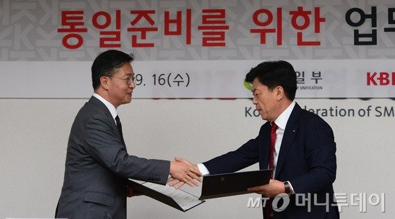 홍용표 통일부 장관과 박성택 중소기업중앙회장이 지난해 9월16일 서울 여의도 중소기업중앙회에서 열린 통일준비를 위한 업무협약식에서 협약서를 교환하고 있다. 양측은 중기중앙회 산하 협회와 조합을 통해 북한 이탈 주민을 채용하는 데 협력하고 통일에 대비해 중소기업이 나아가야 할 방향을 공동 연구하기로 했다. /사진=뉴스1