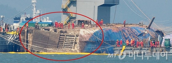 23일 오후 세월호 침몰 해역에서 중국 인양업체 상하이샐비지 작업자들이 바다에 떠오른 세월호 선미 부분을 들여다보고 있다. 해양수산부는 이날 예상치 못하게 개방된 세월호 좌현 선미 램프를 제거하기로 했다./ 사진=공동취재단
