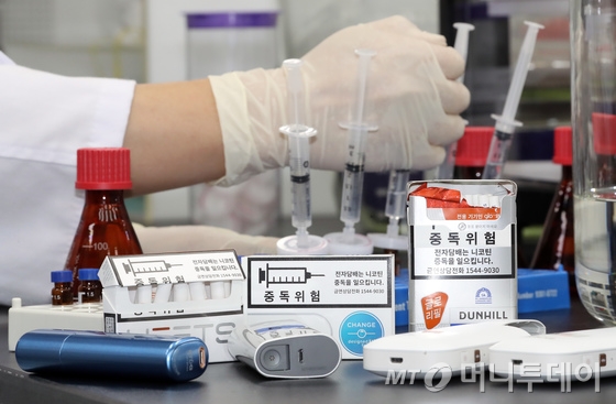 식품의약품안전처 연구원이 7일 충북 청주시 식약처에서 궐련형 전자담배의 배출물 포집 및 추출 과정을 시연하고 있다.   식약처는 국내 판매중인 궐련형 전자담배의 배출물에 포함된 니코틴, 타르 등 11개 유해성분을 분석한 결과 일반담배와 같이 포름알데히드, 벤젠 등 발암물질이 검출됐다고 밝혔다. 또한 궐련형 전자담배 2개 제품의 경우 타르 함유량이 일반담배보다 높게 검출되는 등 건강에 덜 유해하다는 근거가 없다고 설명했다. /사진=뉴스1