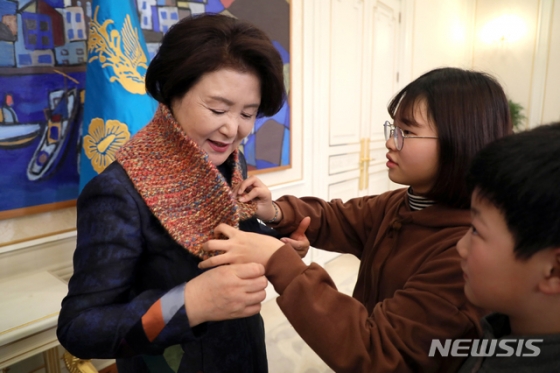 【서울=뉴시스】전신 기자 = 김정숙 여사가 지난 20일 오후 청와대 본관 인왕실에서 광주광역시 서광 지역아동센터 아동을 초대해 격려하는 중 조가영 학생에게 뜨개실로 만든 목도리를 선물받고 있다. 2018.12.23. (사진=청와대 제공)   photo@newsis.com   <저작권자ⓒ 공감언론 뉴시스통신사. 무단전재-재배포 금지.>
