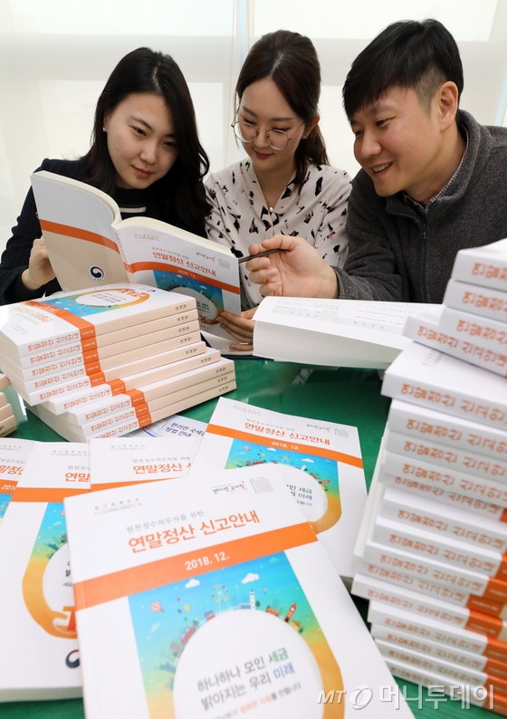 (서울=뉴스1) 이종덕 기자 = 14일 국세청 종로세무서 직원들이 세무서 법인납세과에서 오는 15일 연말정산간소화서비스 개통을 앞두고 연말정산 신고안내 책자를 검토하고 있다. 2018년 귀속 근로소득 연말정산에는 신용카드 소득공제 중 도서공연비 항목이 신설됐고, 중소기업 취업자 소득세 감면 확대, 세액공제 중 중증 질환자 세액공제가  확대되었다.2019.1.14/뉴스1  <저작권자 © 뉴스1코리아, 무단전재 및 재배포 금지>