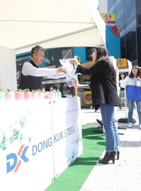 장세욱 동국제강 부회장이 철의 친환경성을 홍보하기 위한 ‘그린 캠페인’ 일환으로 임직원들과 15일 서울 마포에서 한 시민에게 철로 만든 미니 화분을 나눠주고 있다./사진제공=동국제강