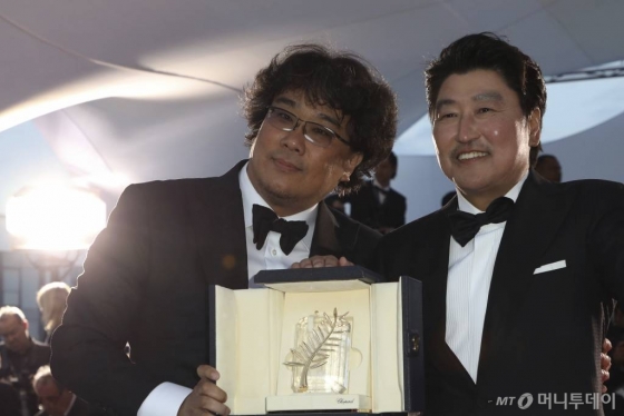 【칸=AP/뉴시스】봉준호(왼쪽) 감독이 25일(현지시간) 프랑스 칸에서 열린 제72회 칸 국제영화제시상식에서 영화 '기생충'으로 '황금종려상'을 받고 배우 송강호와 함께 포즈를 취하고 있다.
