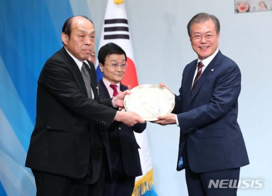 【오사카(일본)=뉴시스】전신 기자 = 문재인 대통령이 27일 오사카 뉴오타니 호텔에서 열린 동포 만찬간담회에서 제15대 심수관으로부터 사츠미 난화도 접시를 선물받고 있다. 2019.06.27.   photo1006@newsis.com