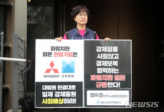 【서울=뉴시스】박미소 기자 = 엄미경 민주노총통일위원장이 17일 오후 서울 종로구 구 일본대사관 인근에서 '일제 강제동원 사죄배상하라'는 문구가 적힌 피켓을 들고 1인 시위를 하고 있다.2019.07.17.  misocamera@newsis.com