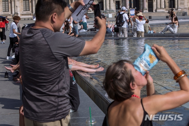 24일(현지시간) 기록적인 폭염이 이어지고 있는 프랑스 파리 루브르 박물관 근처 분수에서 열기를 식히고 있는 사람들의 모습. 2019.07.26.