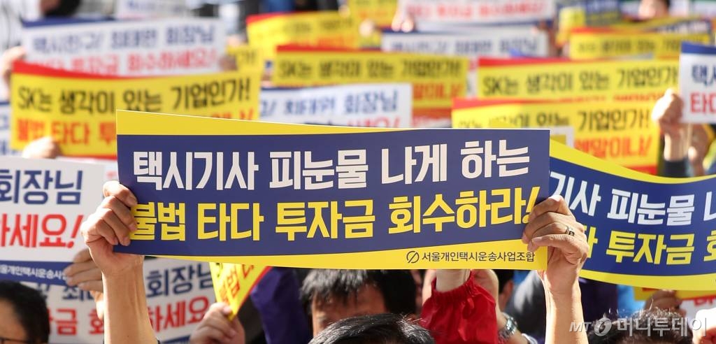 서울개인택시운송사업조합원들이 15일 오전 서울 종로구 SK 본사 앞에서 '불법 타다 투자한 SK 기업 규탄대회'를 열고 구호를 외치고 있다./2019-10-15 / 사진=김휘선 기자 hwijpg@