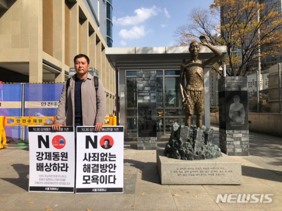 【서울=뉴시스】한 겨레하나 회원이 29일 서울 용산구 용산역 부근 강제징용노동자상 앞에서 일본 정부와 기업들이 강제동원 배상판결을 이행할 것을 촉구하며 1인 시위를 하고 있다. 2019.10.29. (사진=겨레하나 제공)  photo@newsis.com