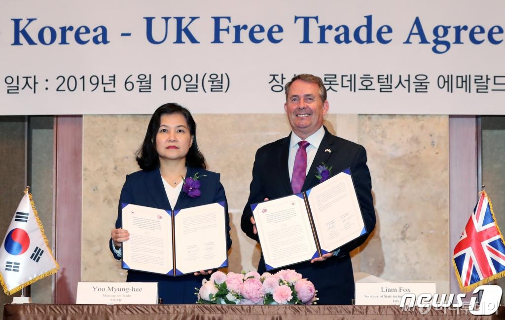 유명희 산업통상자원부 통상교섭본부장과 리암 폭스(Liam Fox)영국 국제통상부 장관이 10일 오전 서울 중구 롯데호텔에서 열린 '한-영 자유무역협정 원칙적 타결 선언식'에서 협약서에 서명 후 환하게 웃고 있다.  한국과 영국의 자유무역협정(FTA)이 원칙적 타결을 이뤄냈다. 한영 FTA는 영국이 아무런 합의 없이 유럽연합(EU)을 탈퇴하는 이른바 '노딜 브렉시트'에 대비한 임시 조치(emergency bridge agreement)로 기존 한-EU FTA 수준의 협정을 통해 양국 통상관계의 연속성과 안정성을 확보할 수 있게 됐다. 2019.6.10/사진=뉴스1