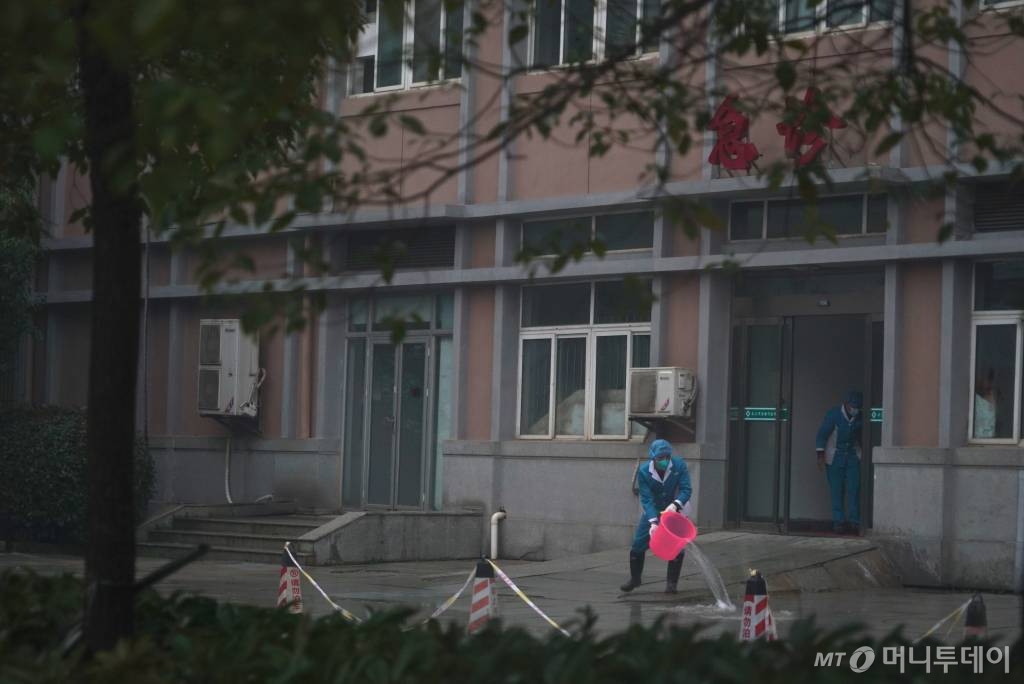 [우한=AP/뉴시스] 신종 코로나바이러스가 원인균으로 알려진 폐렴에 감염된 환자들이 수용돼 있는 중국 우한치료센터(Wuhan Medical Treatment Center)의 22일 외부 모습. 보호복을 입은 사람이 물을 끼얹고 있다. 2020.01.23