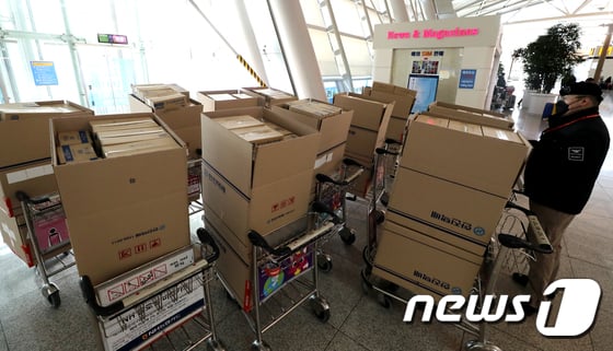 6일 오전 인천국제공항 여객터미널 출국장 입구에 마스크 박스가 쌓여있는 가운데 인천공항 경비 관계자들이 마스크를 유실물센터로 옮기고 있다. / 사진 = 뉴스 1