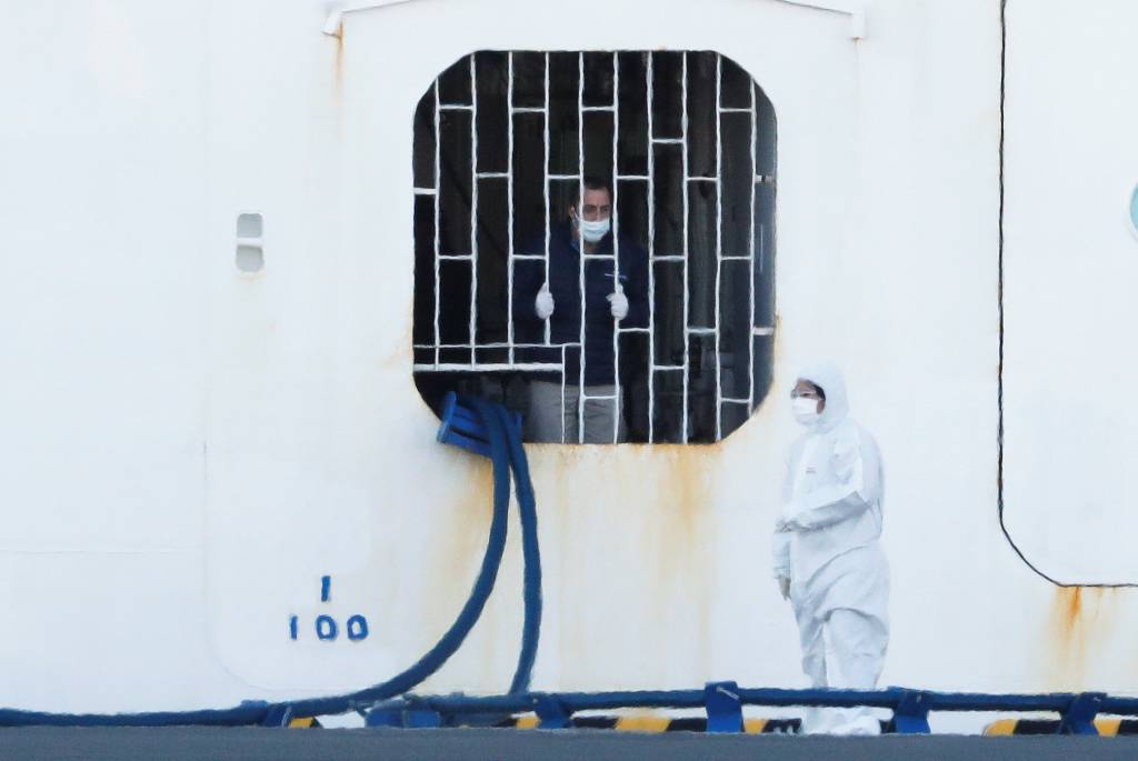 10일 일본 요코하마 항구에 정박 중인 '다이아몬드 프린세스'에서 한 선원(왼쪽)이 보호장비를 갖춘 근로자에게 말을 걸고 있다. 지난달 20일 이곳을 출발했던 이 크루즈선은 중간에 홍콩에서 내린 홍콩인이 신종 코로나 바이러스 확진 판정을 받으면서, 바이러스 확산 우려로 출발지로 돌아온 후에도 승객(승무원 포함) 전원이 내리지 못하고 있다. 약 3700명의 승객 중 확진자는 이날 60명이 늘면서 총 130명이 됐다. / 사진제공=로이터