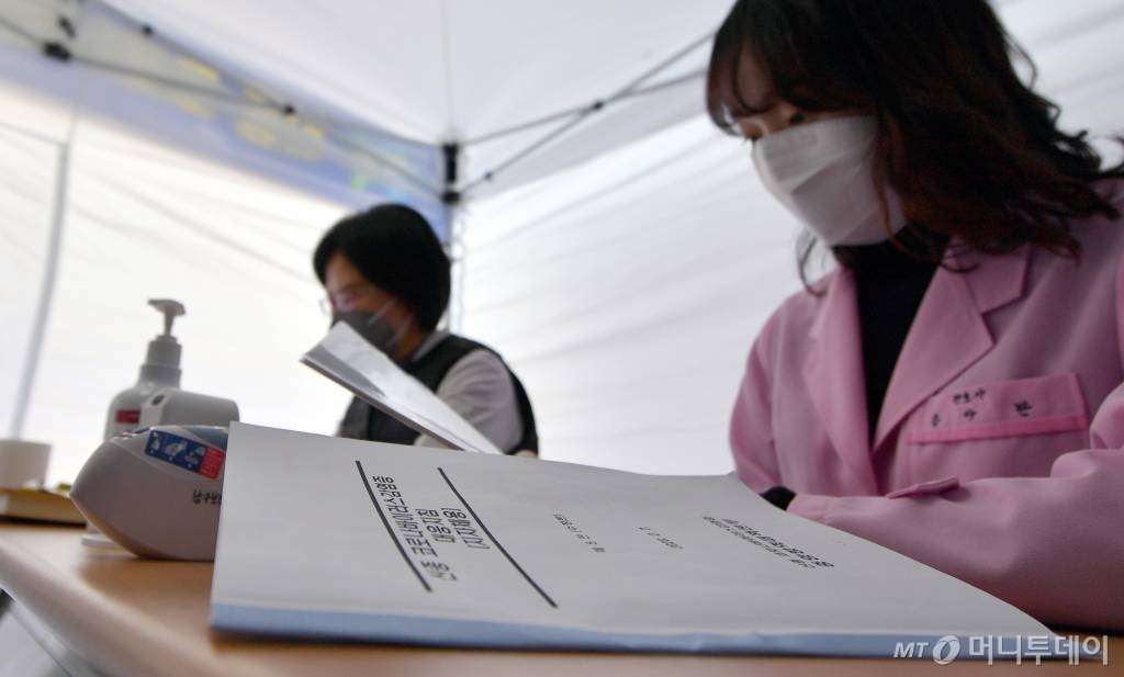 [광주=뉴시스] 류형근 기자 = 신종 코로나 바이러스 감염증 선별진료 범위가 중국외 지역으로 확대된 가운데 9일 오전 광주 남구 남구청사 앞 선별진료소에서 의료진이 관련 매뉴얼을 숙지하고 있다. 2020.02.09.   hgryu77@newsis.com