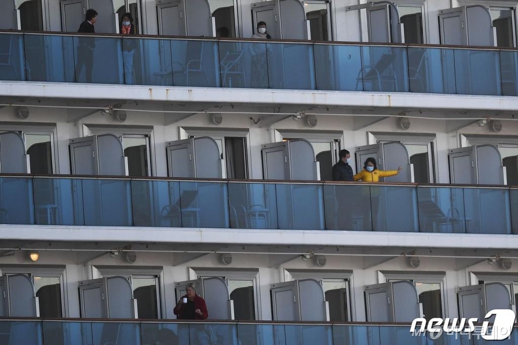 (요코하마 AFP=뉴스1) 우동명 기자 = 11일(현지시간) 신종 코로나바이러스 감염자 급증으로 요코하마항 앞바다에 격리 형태로 정박 중인 크루즈선 다이아몬드 프린세스호의 승객들이 밖을 내다보고 있다.   © AFP=뉴스1  <저작권자 © 뉴스1코리아, 무단전재 및 재배포 금지>
