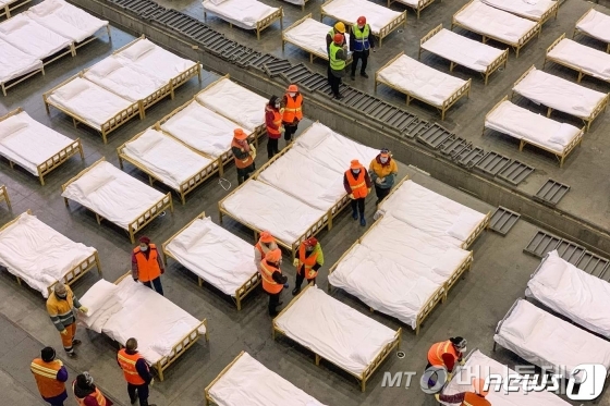 (우한 AFP=뉴스1) 정윤미 기자 = 중국 후베이성 우한시 정부는 신종 코로나바이러스 확진자 수용을 위해 기존의 체육관, 전시회장 등 3곳을 간이 병원으로 사용하라고 지시했다. 이에 따라 4일(현지시간) 정부 관계자들은 전시회장이었던 공간에 병상을 배치하고 있다. ⓒ AFP=뉴스1 <저작권자 ⓒ 뉴스1코리아, 무단전재 및 재배포 금지>