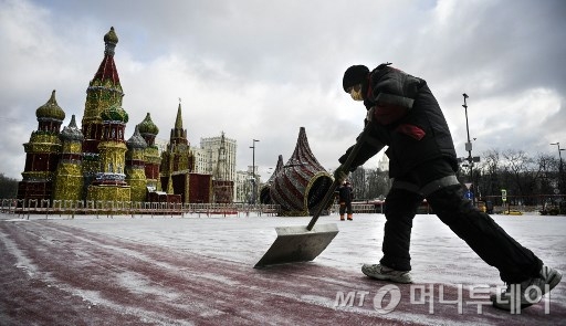 지난 7일 러시아 모스크바의 성바실성당 앞에서 한 근로자가 의료용 마스크를 쓰고 눈을 치우고 있다. 블라디미르 푸틴 러시아 대통령은 지난 7일 코로나19 사태에 따라 의료용 마스크 가격을 임의로 올린 약국에 대해 폐쇄 조치를 취하겠다고 밝혔다./사진=AFP