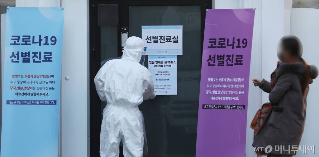 [서울=뉴시스] 조수정 기자 = 신종 코로나 바이러스 감염증(코로나 19) 국내 확진자가 18일 오전 기준 31명, 그중 10명이 퇴원했다. 18일 오후 서울 중구 국립중앙의료원 보호복을 입은 의료진이 한 여성과 함께 선별진료소로 들어가고 있다. 2020.02.18.   chocrystal@newsis.com