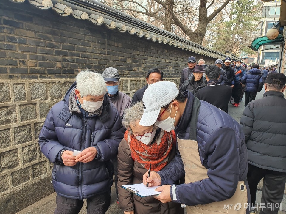 21일 원각사 노인무료급식소 직원이 노인들 전화번호를 받고 있다. 급식소 잠정 폐쇄가 종료되면 다시 연락하기 위함이다. /사진=정경훈 기자