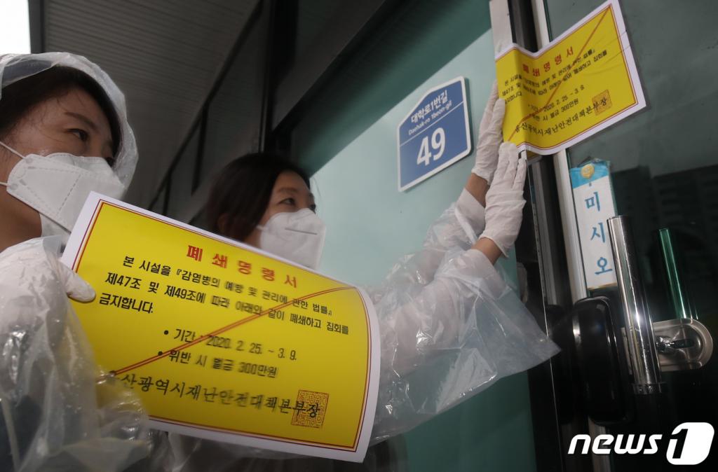 25일 신종 코로나바이러스 감염증(코로나19) 울산 확진자가 4명으로 늘어난 가운데 울산시청 공무원들이 남구 무거동 신천지 울산교회 출입문에 폐쇄명령서를 붙이고 있다. /사진=뉴스1