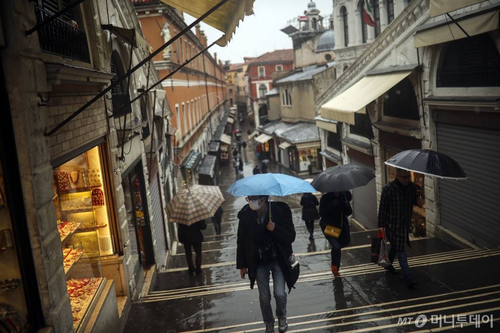 [베네치아=AP/뉴시스]1일(현지시간) 이탈리아 북부 베네토주 베네치아에서 시민들이 마스크를 착용하고 우산을 쓴 채 걷고 있다. 이 지역에서는 신종 코로나바이러스 감염증(코로나19) 확진자가 다수 나왔다. 2020.03.02.