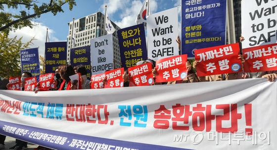 법무부가 제주에서 난민 신청을 한 예멘인 중 330명에게 인도적 체류허가를 내린 18일 서울 종로구 정부서울청사 앞에서 난민대책국민행동 등 시민단체 회원들이 정부의 예멘인 난민심사 결정에 대한 긴급 기자회견을 하고 있다.   이번 기자회견에서 시민단체 회원들은 "가짜 난민은 단 한 명도 우리 땅을 밟아서는 안된다"며 "소셜네트워크(SNS)에 총기사진 등을 올린 이들을 즉시 송환해야한다"고 밝혔다. 2018.10.18/뉴스1