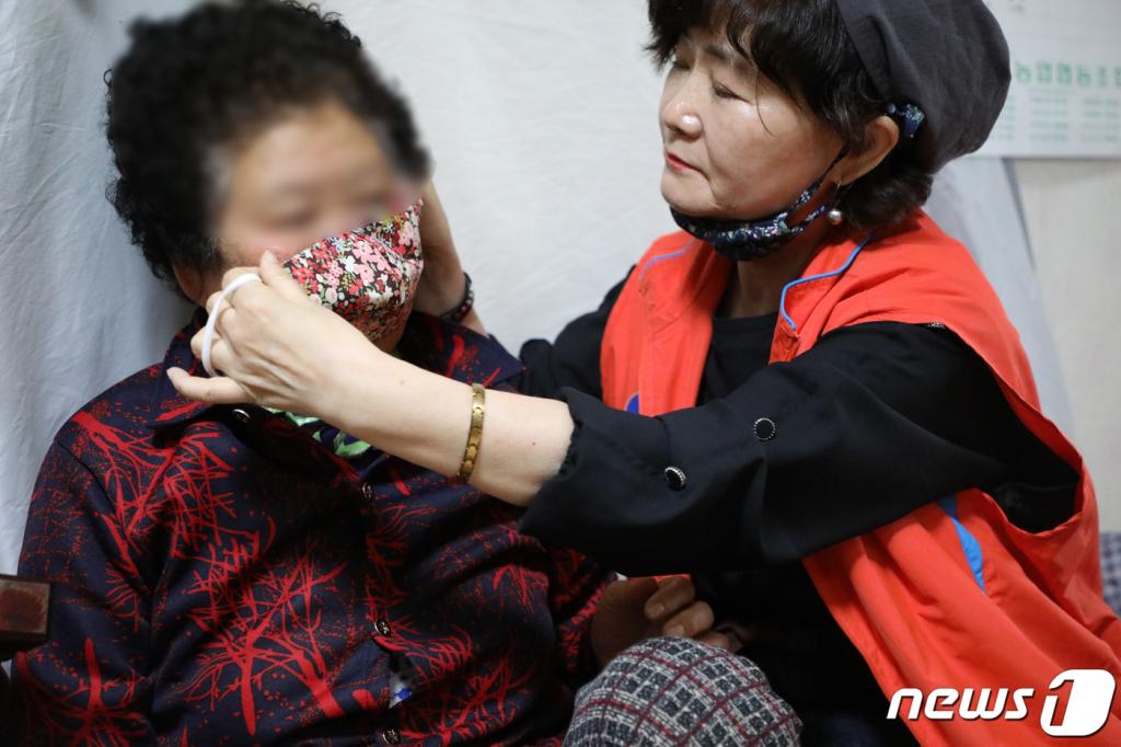 (광주=뉴스1) 허단비 기자 = 9일 오후 광주 서구 서창동 한 가정집에서 강미자 서창동 보장협의체 위원장(가운데)이 취약계층 어르신들에게 직접 만든 마스크를 씌워드리고 있다. 2020.3.9/뉴스1