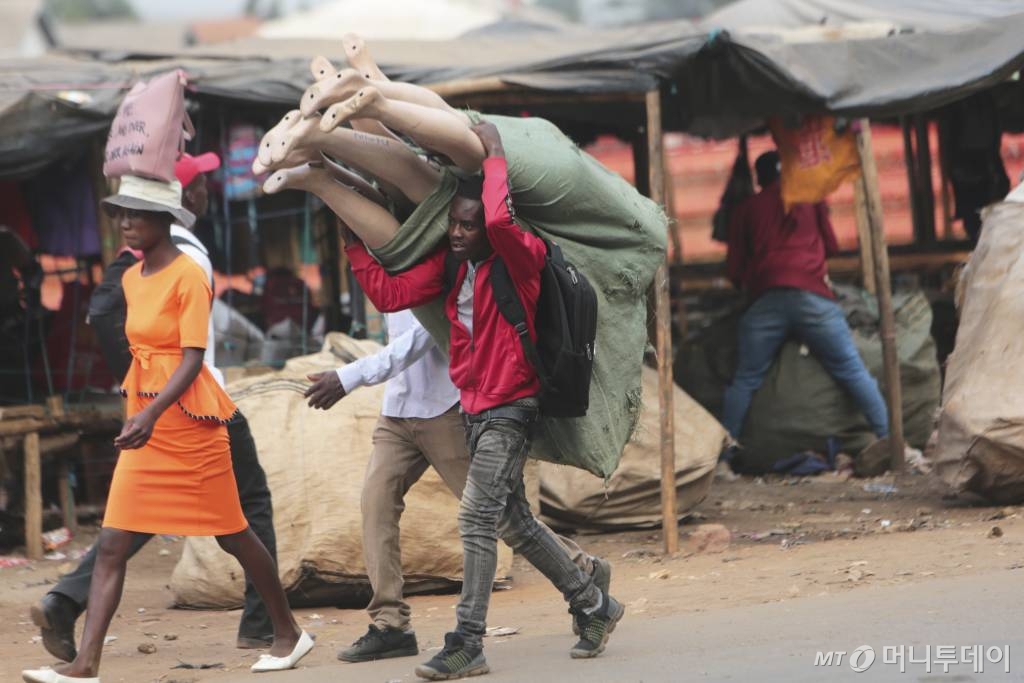 [하라레=AP/뉴시스]2일(현지시간) 짐바브웨 수도 하라레에서 한 남성이 마네킹 꾸러미를 어깨에 짊어지고 가고 있다. 2020.03.03.