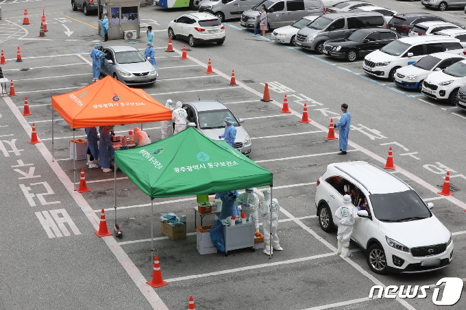 6일 오전 광주 동구청 드라이브 스루 선별진료소에서 구청 보건소 직원들이 차량에 탄 시민과 아이들을 상대로 검체를 채취하고 있다. 방역당국에 따르면 전날 오후 금양오피스텔 관련 광주 110번 확진자의 외손주 2명이 코로나19 양성 판정을 받았다. 이에 동구는 아동 확진자들이 다니는 어린이집 원생과 보육교직원 등에 대해 검사를 실시했다. 2020.7.6 /뉴스1 © News1 황희규 기자