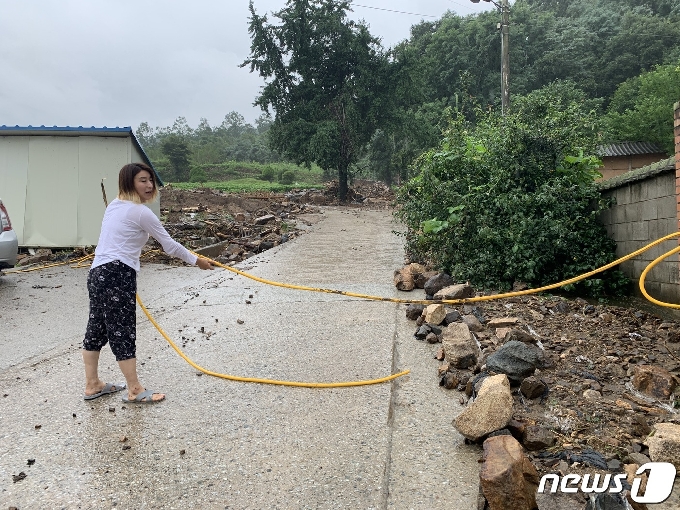 3일 충북 엄정면 비석마을에 사는 서은주씨가 1~2일 폭우에 집 앞 도로가 강으로 변했다며 수도 호스를 이용해 탈출했던 당시 상황에 대해 설명하고 있다.2020.8.3/ © 뉴스1