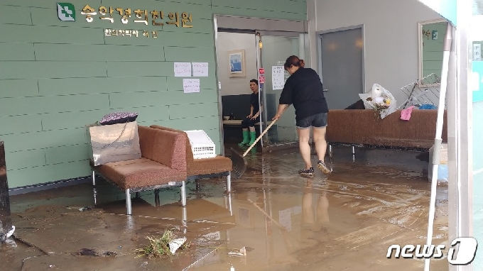 시간당 최대 90㎜내외의 폭우가 쏟아진 충남 아산 송악면 외삼리에 위치한 한의원 직원들이 건물 안까지 들이친 빗물을 빼내고 있다. © 뉴스1