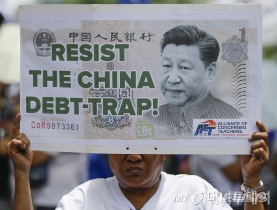 【마닐라=AP/뉴시스】필리핀 독립기념일인 201년6월12일(현지시간) 필리핀 마닐라 시내 금융가 마카티의 중국 영사관 밖에서 한 시위 참가대가 "중국의 부채 덫"에 걸리지 말자는 구호가 쓰인 시진핑 중국 국가 주석이 나온 인민폐 모형을 들고 시위하고 있다.