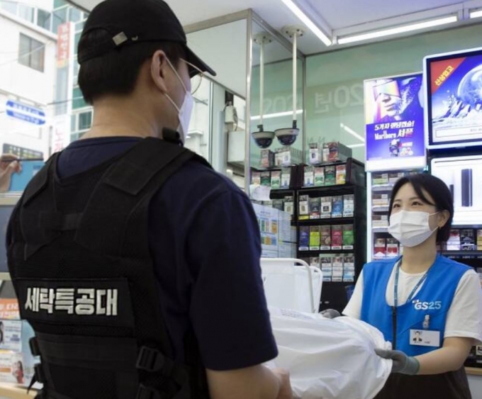 GS25 직원이 세탁특공대 직원에게 고객의 세탁물을 전달하고 있다/사진제공=GS리테일