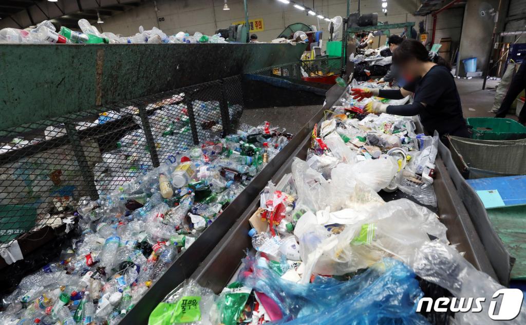 (서울=뉴스1) 이동해 기자 = 4일 오후 서울 송파구 송파자원순환공원에서 쓰레기선별업체 근로자가 재활용쓰레기 선별장에 쌓인 쓰레기를 분류하고 있다.  신종 코로나바이러스 감염증(코로나19)의 여파로 만들어진 '언택트'가 세상을 바꾸고 있다. 대면보다는 비대면, 오프라인보다는 온라인이 활성화되면서 전에 볼 수 없던 양상이다.  하지만 거리두기로 부상한 언택트 소비가 재활용쓰레기업계의 골칫덩이가 되고 있다. 송파구자원순환공원에서 하루에 처리할 수 있는 재활용쓰레기양은 70t이지만 3월에만 하루 평균 87t의 쓰레기가 반입됐다.  이는 택배와 배달음식 소비가 증가하면서 재활용쓰레기 반입량이 크게 늘었기 때문으로 파악됐다. 송파구청 역시 늘어나는 쓰레기를 예의 주시하지만 뾰족한 대책은 없는 상태. 이미 우리나라의 매립지는 포화 직전 상태이며 쓰레기 매립지는 대표적인 님비(NIMBY) 시설이기 때문에 신설도 어렵다. 코로나19에 대한 우리들의 걱정과 두려움은 당연하지만 그럼에도 불구하고 폭발적으로 늘어나고 있는 플라스틱 쓰레기에 대해서도 경각심을 가져야 한다. 2020.5.4/뉴스1