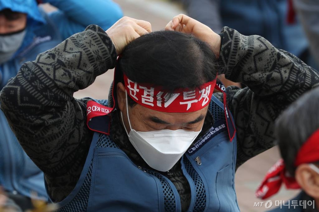 [서울=뉴시스]이윤청 기자 = 전국택배연대노동조합 조합원들이 27일 서울 송파구 서울복합물류센터에서 열린 롯데택배 전국 파업출정식에서 '단결투쟁'이 적힌 머리띠를 묶고 있다. 2020.10.27.   radiohead@newsis.com