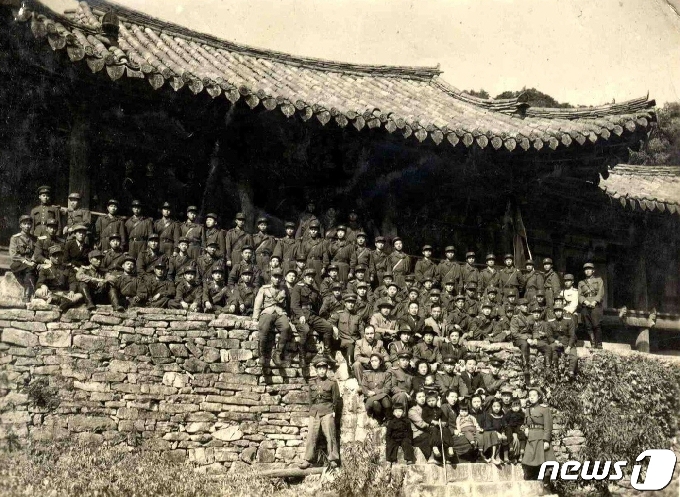 1949년 10월 김일성 수상이 인민군 대원들과 함께 천주사를 방문해 천주루 앞에서 기념촬영하고 있다. 4번째 줄 가운데에 김일성 수상이 앉아 있고, 맨 앞줄에 어린 김정일(왼쪽에서 3번째)의 모습이 보인다. (미디어한국학 제공) 2020.12.12.© 뉴스1