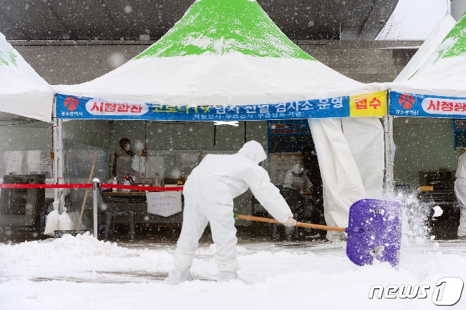 시간당 1㎝가 넘는 눈이 내려 적설량 14㎝를 기록한 30일 오전 광주광역시 서구 광주시청 앞에 설치된 임시선별진료소에서 의료진들이 제설 작업을 하고 있다.2020.12.30/뉴스1 © News1 정다움 기자