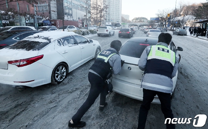7일 오전 경기도 수원시 영통구 광교로에서 경찰들이 밤사이 내린 눈으로 언덕 길에서 미끄러지는 차량들을 밀고 있다. 2021.1.7/뉴스1 © News1 조태형 기자