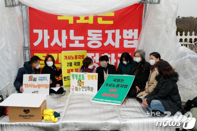 (서울=뉴스1) 안은나 기자 = 22일 서울 여의도 국회의사당 앞에서 '가사노동자 권리보장법 2월 통과를 위한 여성·노동·시민사회단체 기자회견' 참가자들이 기자회견 시작 전 농성장에 앉아있다. 여성·노동·시민사회단체는 가사노동자도 존중받으며 안전하고 건강하게 일할 권리가 있음에도 고용유지지원금이나 실업급여는 커녕 재난지원금에서조차 배제되고 있다며 국회가 2월 중에 '가사노동자고용 개선 등에 관한 법률'을 통과시켜야 한다고 주장했다. 2021.2.22/뉴스1